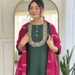 Young woman exploring fashion through ethnic wear, wearing an elegant dark green kurti with detailed neckline embroidery and a deep pink dupatta, styled with statement earrings.