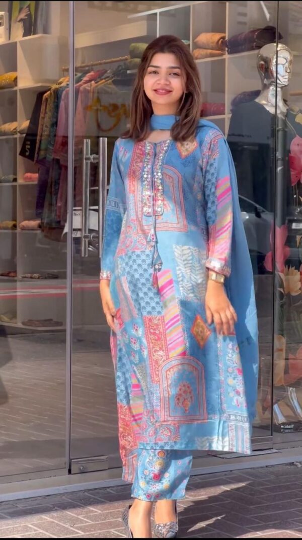 Young woman wearing a sky blue multicolor printed kurti suit from the kurti-suits-collection-2025, paired with matching pant and dupatta, posing confidently in front of a boutique.