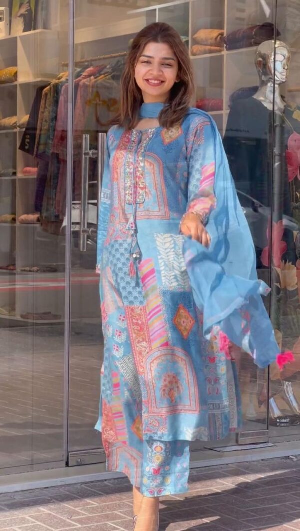 Young woman wearing a sky blue multicolor printed kurti suit from the kurti-suits-collection-2025, paired with matching pant and dupatta, posing confidently in front of a boutique.